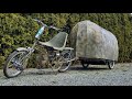 A bicycle camper pulled by a motorized custom tow bike.