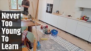 New apprentice helps to put down the kitchen floor