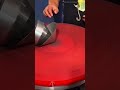 spinning a metal sheet piece into a cone shape using an automatic lathe machine on a workshop