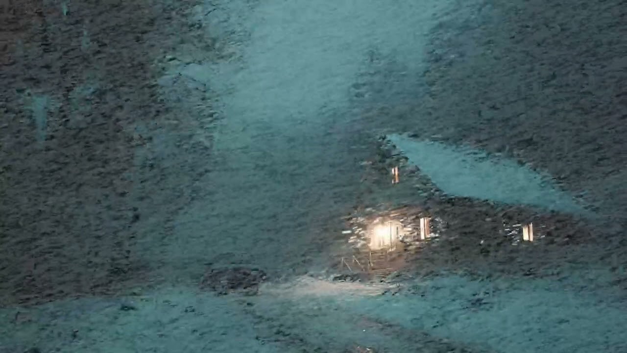 Isolated Forest Cabin Glowing Through the Dark Silent Winter Blizzard on a Snow Covered Road
