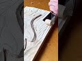 carving a beautiful wave pattern on a flat wooden panel surface with a sharp hand chisel tool