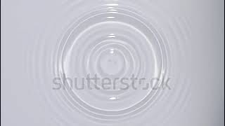 Top view of drop falls into water and diverging circles of water on white background in slow motion