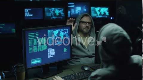 Two Hackers in Hoods Work on Computers with Data on Display Screens in Office Room | Stock Footage