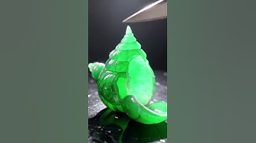 Green emerald shaped like a snail shell sliced cleanly by sharp knife