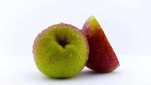 One and the Half of Pear Fruit in Water Drops. Rotating on the Turntable. Isolated on the White |