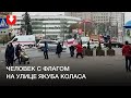 Человек держит флаг на улице Якуба Коласа в Минске