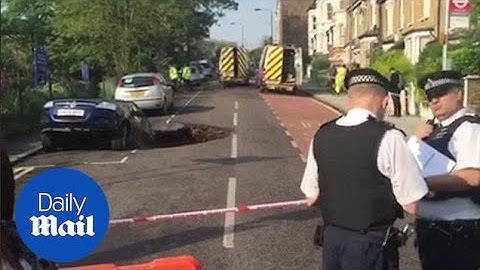 Police probe giant sinkhole that swallowed car on London street - Daily Mail