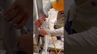 Worker aligning granite wall panel with spirit level for precise installation on metal frame structu
