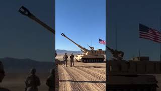 A self-propelled howitzer fires a high-angle shot straight into the desert sky