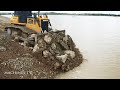 Mind blow operator bulldozer moving stone into water preparing base boundary landfill in big lake