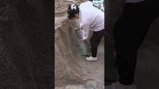 A tireless mother keeps working with spirit, bagging sand carefully for the day’s humble trade daily
