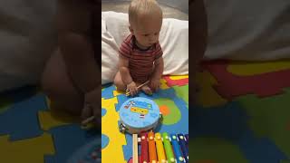 Baby boy plays with piano drumstick toy then falls forward and faceplants