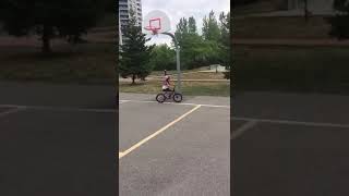 Little girl on bike accidentally crashes into pole of basketball hoop