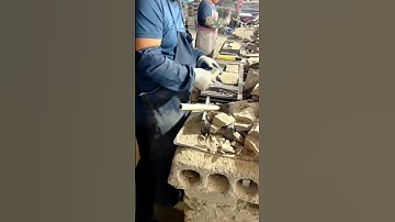 Workers Shaping Stone Pieces Manually Using Hammers and Chisels in a Workshop