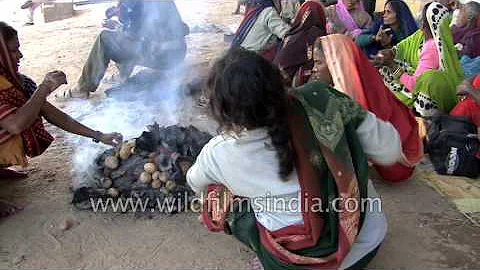 Indian women cook potatoes by burning cow dung patties
