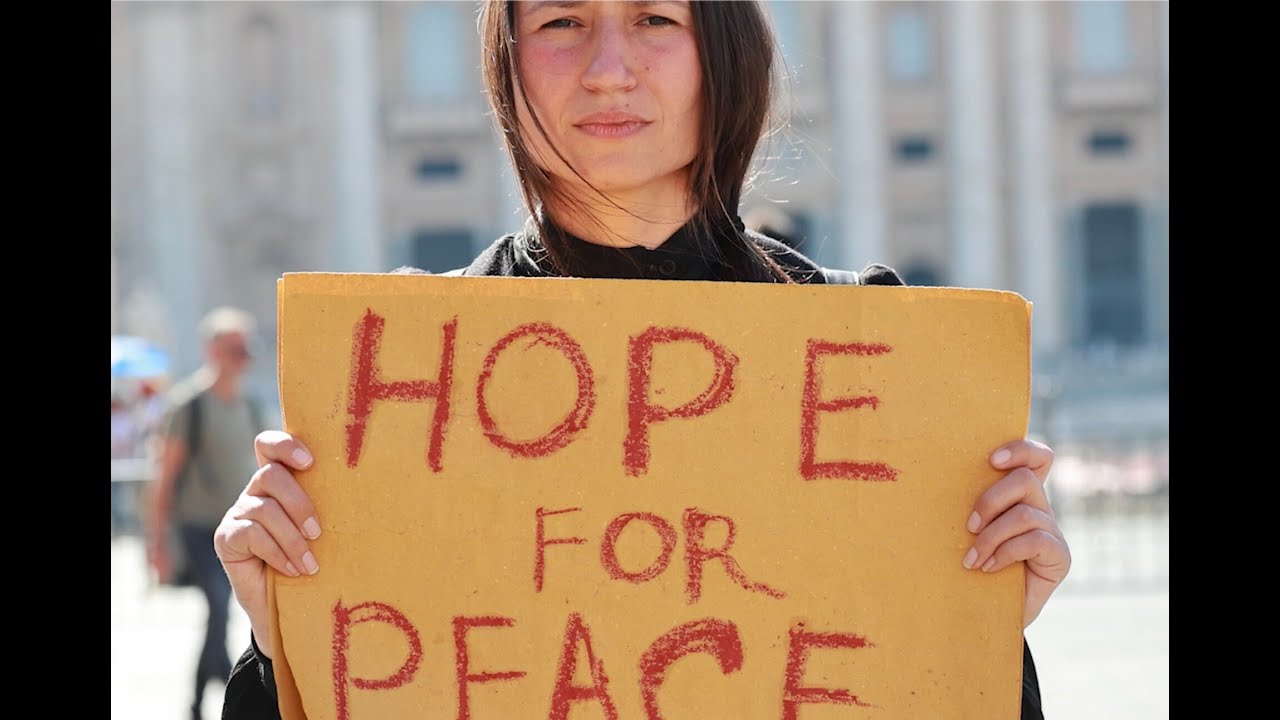 Yona Tukuser holds a "HOPE FOR PEACE" sign in St. Peter's Square at the Vatican during the Conclave