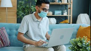 Middle Eastern man in medical mask talking online making video call from home showing thumbs-up