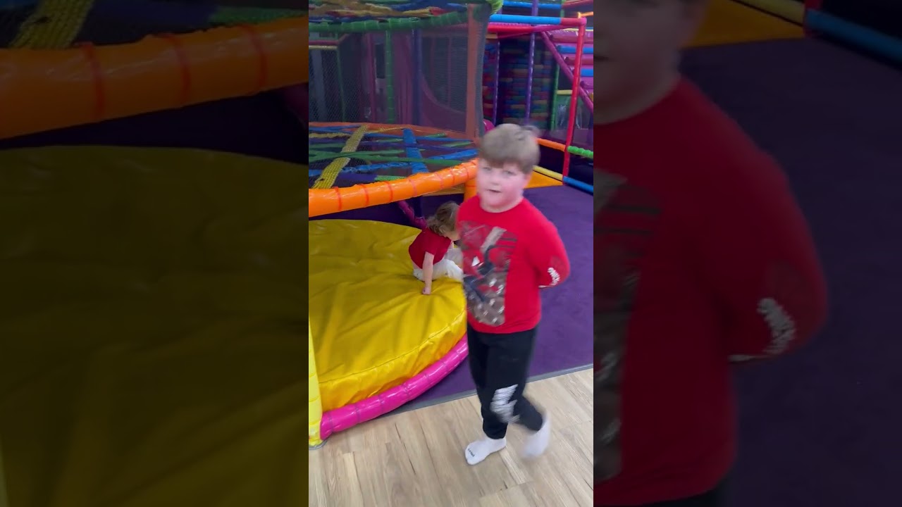Little boy in red shirt falls through maze at indoor playground