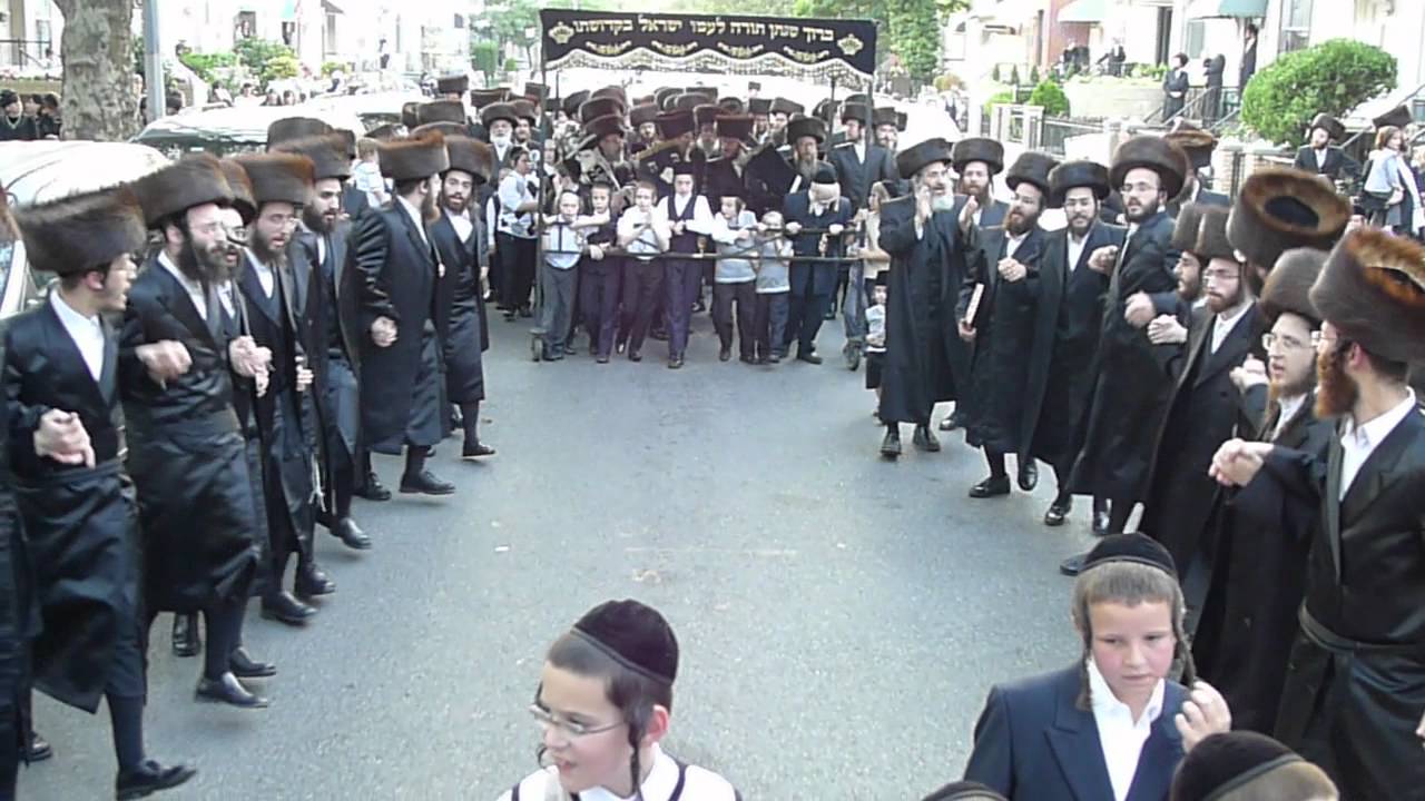 belz chasidim dancing in streets of boro park with sifrei torahs moving to new shteebel boro torah dance