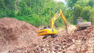 Komatsu Excavator operator cuts through mountains full of rocks to continue the road