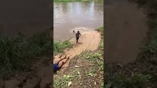Rural kids sliding on the mud into a river.!