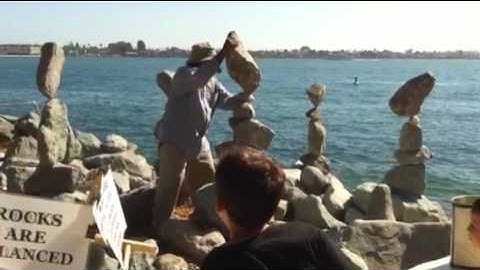 Man balances rocks by the beach