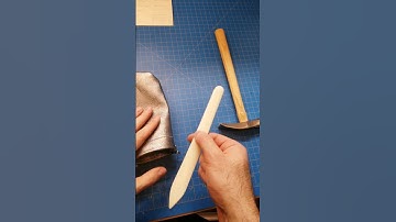 Using a bone folder tool to help complete a leather evening bag.