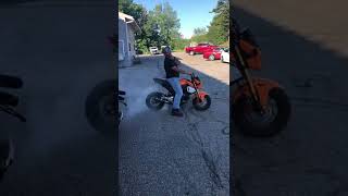 Guy bumps his friend's rear wheel of motorcycle as it's burning out and sends him out of the picture