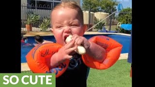 Baby attempts to eat banana while wearing floaties