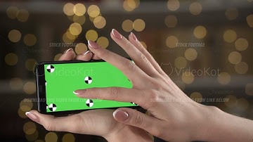 Woman holds smartphone with tracking markers in hands and zooms content by fingers to find something