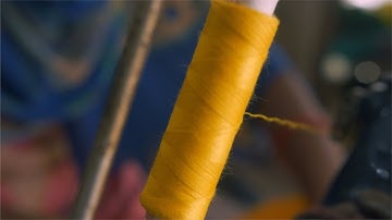 Closeup shot of a spool with thin yellow thread on a professio... | Indian Stock Footage | Knot9