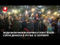 Люди включили фонарики и поют возле статуи дракона в Уручье вечером 12 сентября