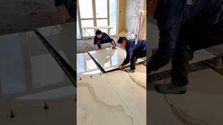 two workers installing large marble pattern floor tiles in a building interior #shorts