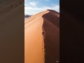 A hiker climbing up a sand hill