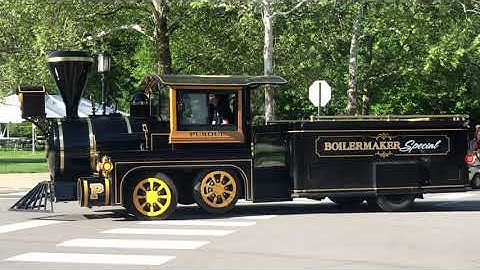 Purdue graduates walking into Elliott Hall behind boiler train