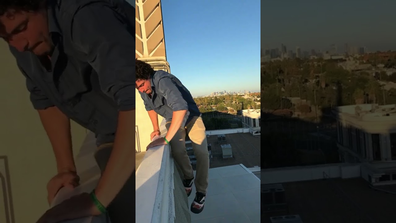 Guy climbs off railing of balcony then falls through roof