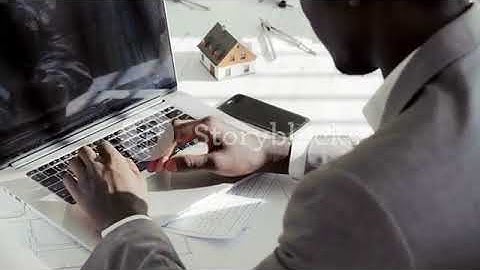 close up of young black businessman hands typing on laptop computer keyboard in white modern office
