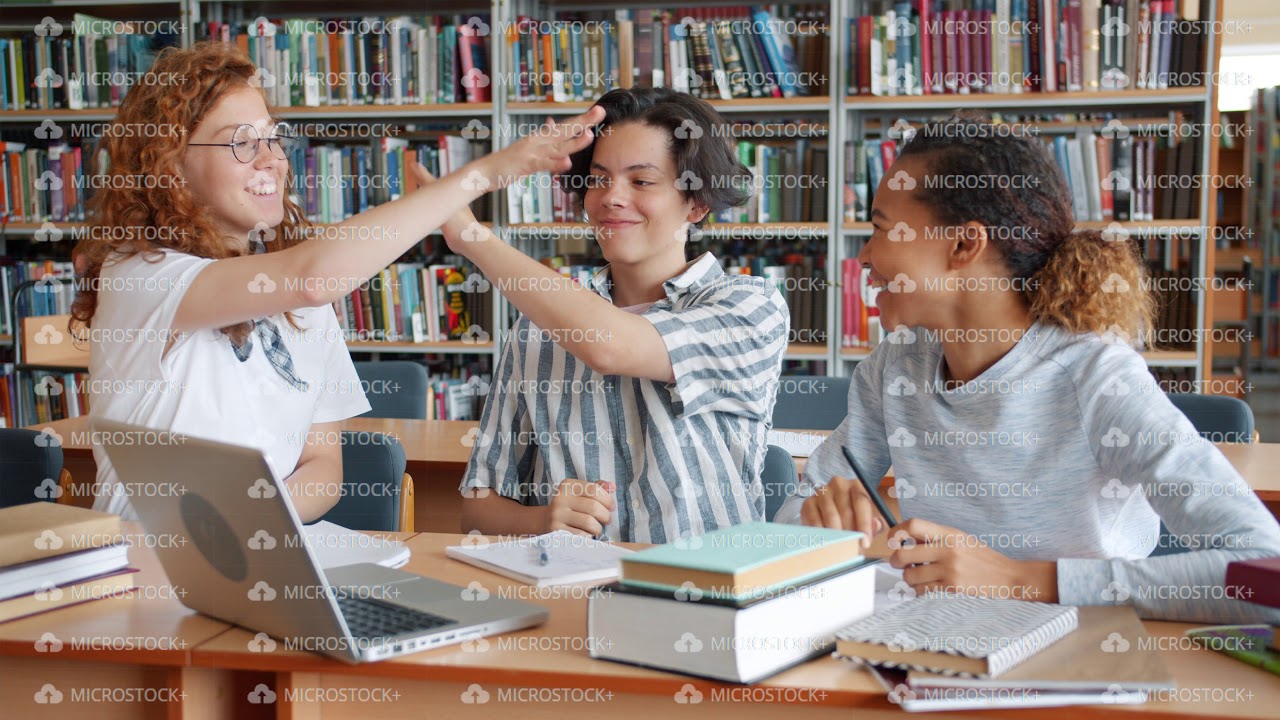 Slow motion of happy students studying in library doing high-five ...
