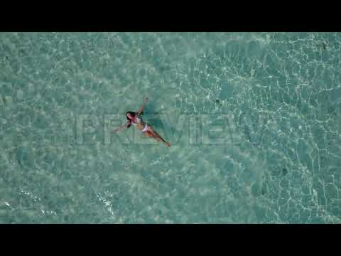 Woman Floating In Tropical Water Aerial | Stock Video - Motion Array