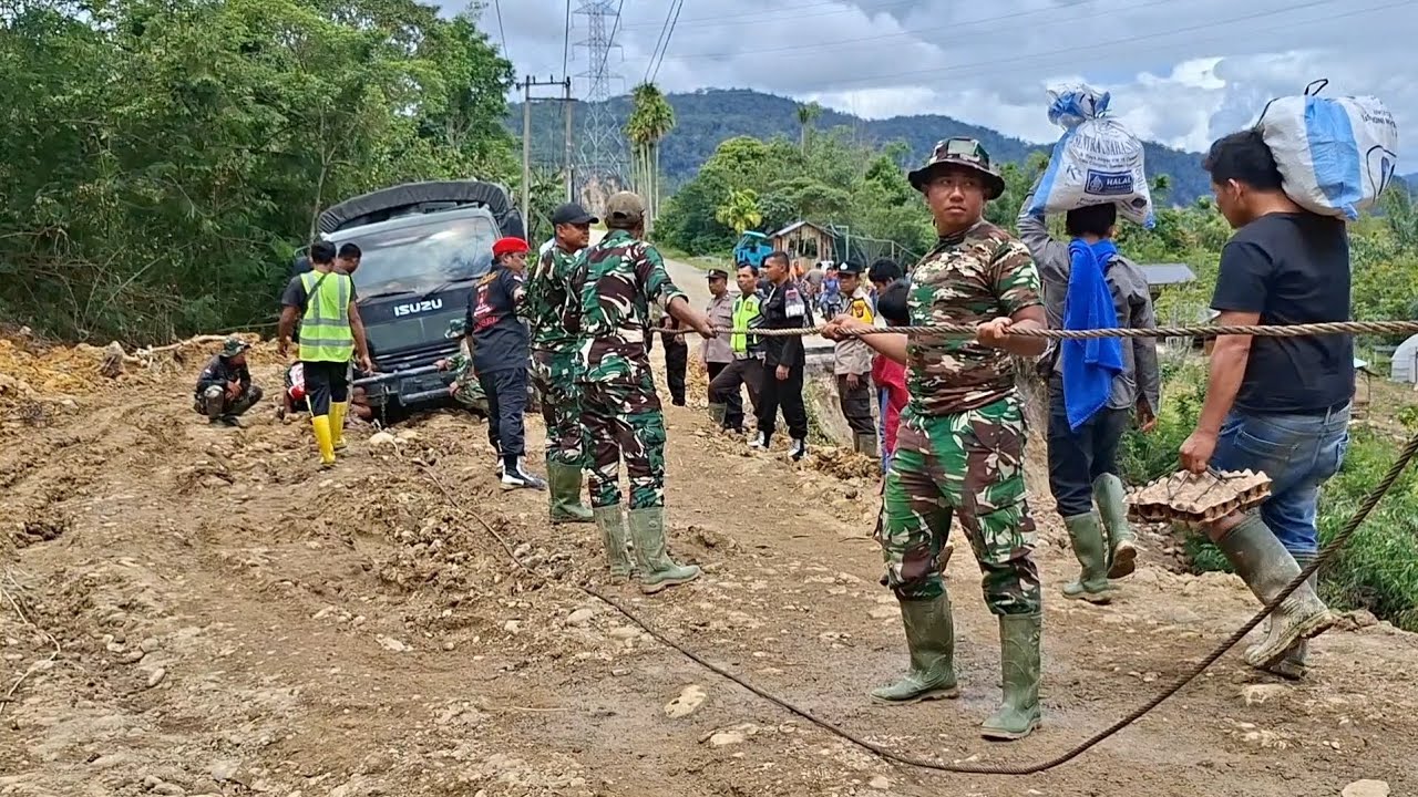 EVAKUASI- truk tni dan truk book terpuruk disamping jalan yg terputus akibat bencana alam