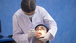 Indian Doctor - The dentist checking the teeth of a young man with a mirror