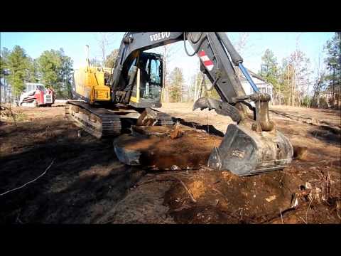 volvo-140-excavator-wrestles-massive-boulder