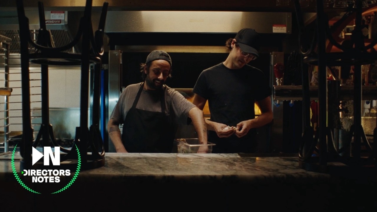 Two actors in a quiet restaurant kitchen after hours, warmed by a pizza oven and practical lamps