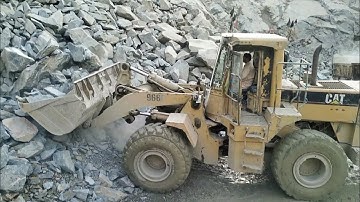 Heavy machine rocks loading in action: caterpillar lodar 966F rock loading trolley and rock sleeping