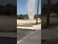 Towering Dust Devil Swirls Through Dirt Lot and Moves Toward Road