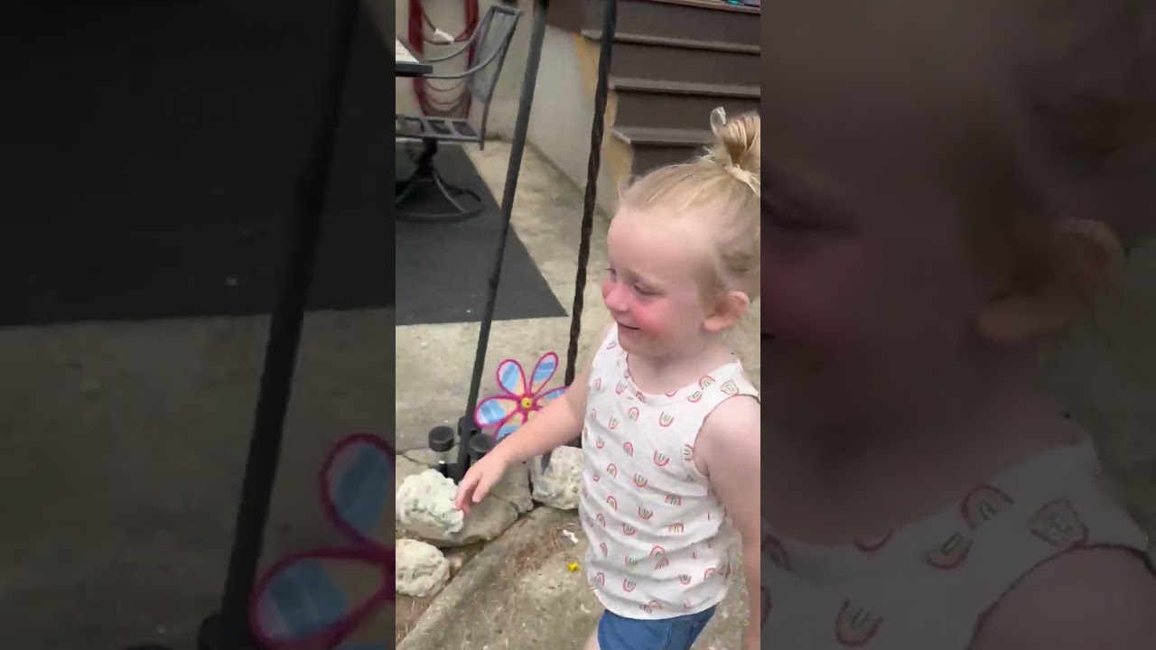 Girl runs in excitement towards swing of jungle gym in backyard then bumps head on green pole