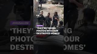 Israeli soldiers take photos while Palestinian homes are being demolished behind them