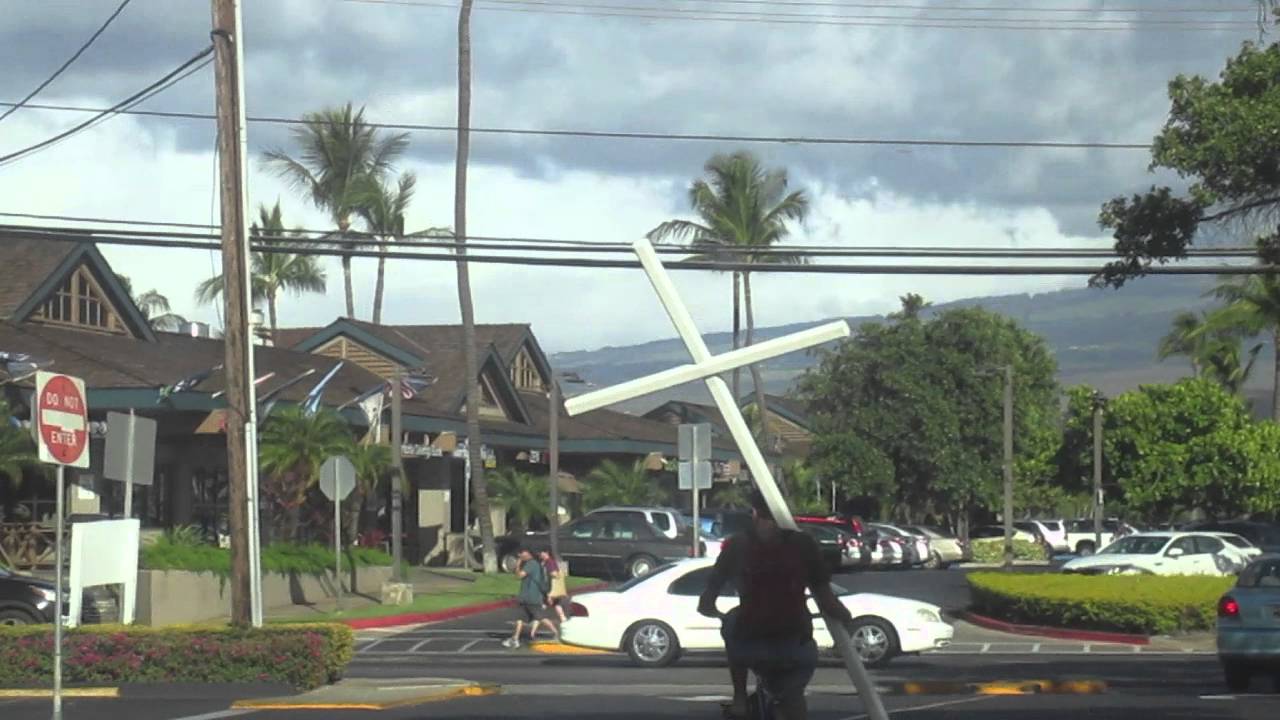 Guy rides around Maui with Giagantic Cross.