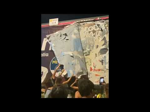 Protesters tearing down a billboard poster of fascist politician