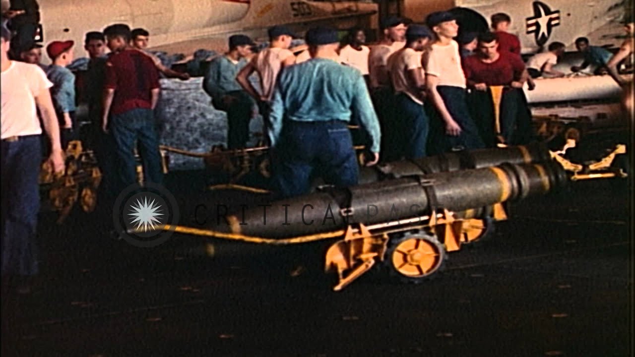 Forklift loaded with ammunition backs off and bombs in carts on hangar bay of USS...HD Stock